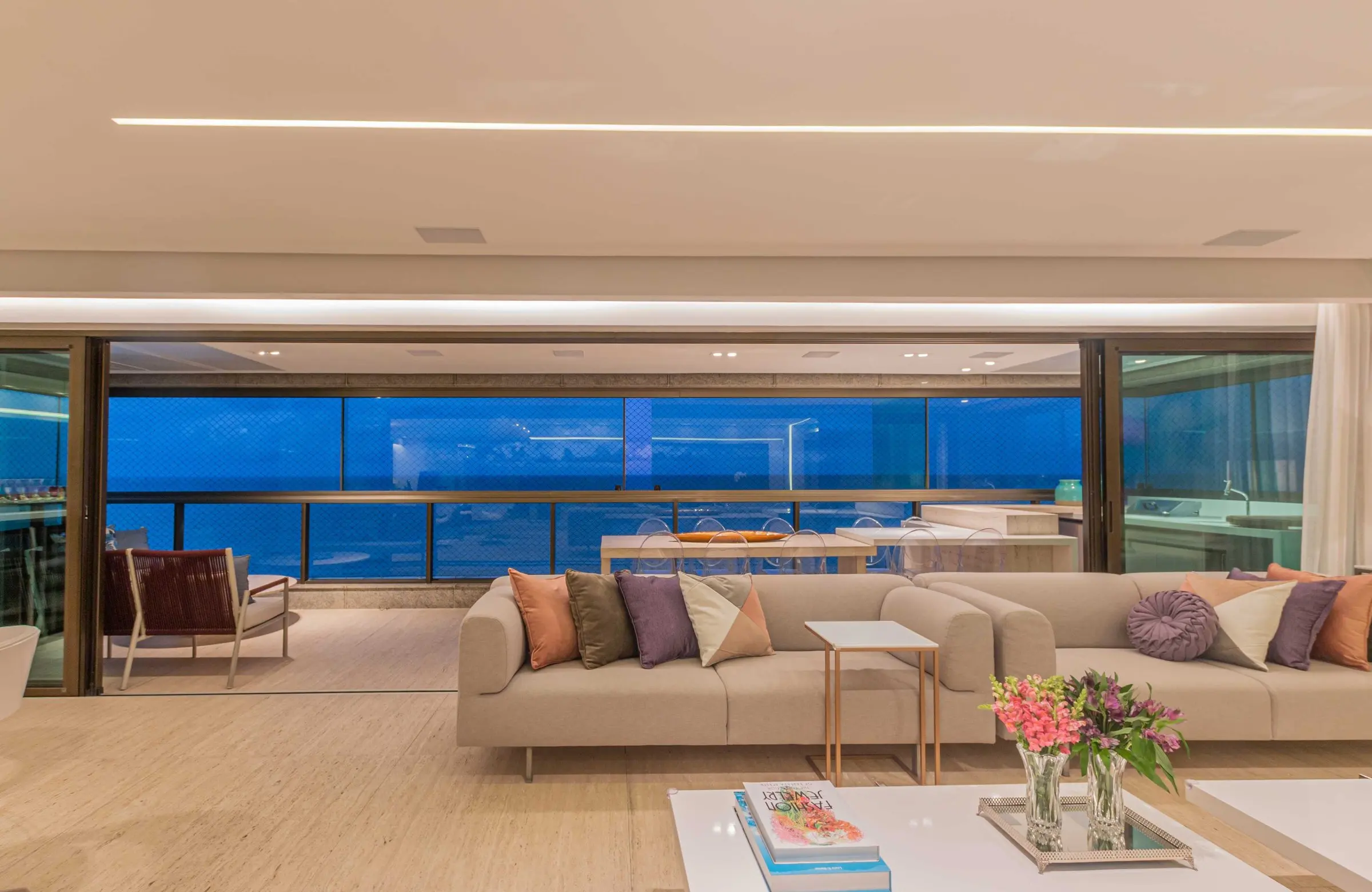 Sala de estar com almofadas coloridas e vista para o mar ao entardecer