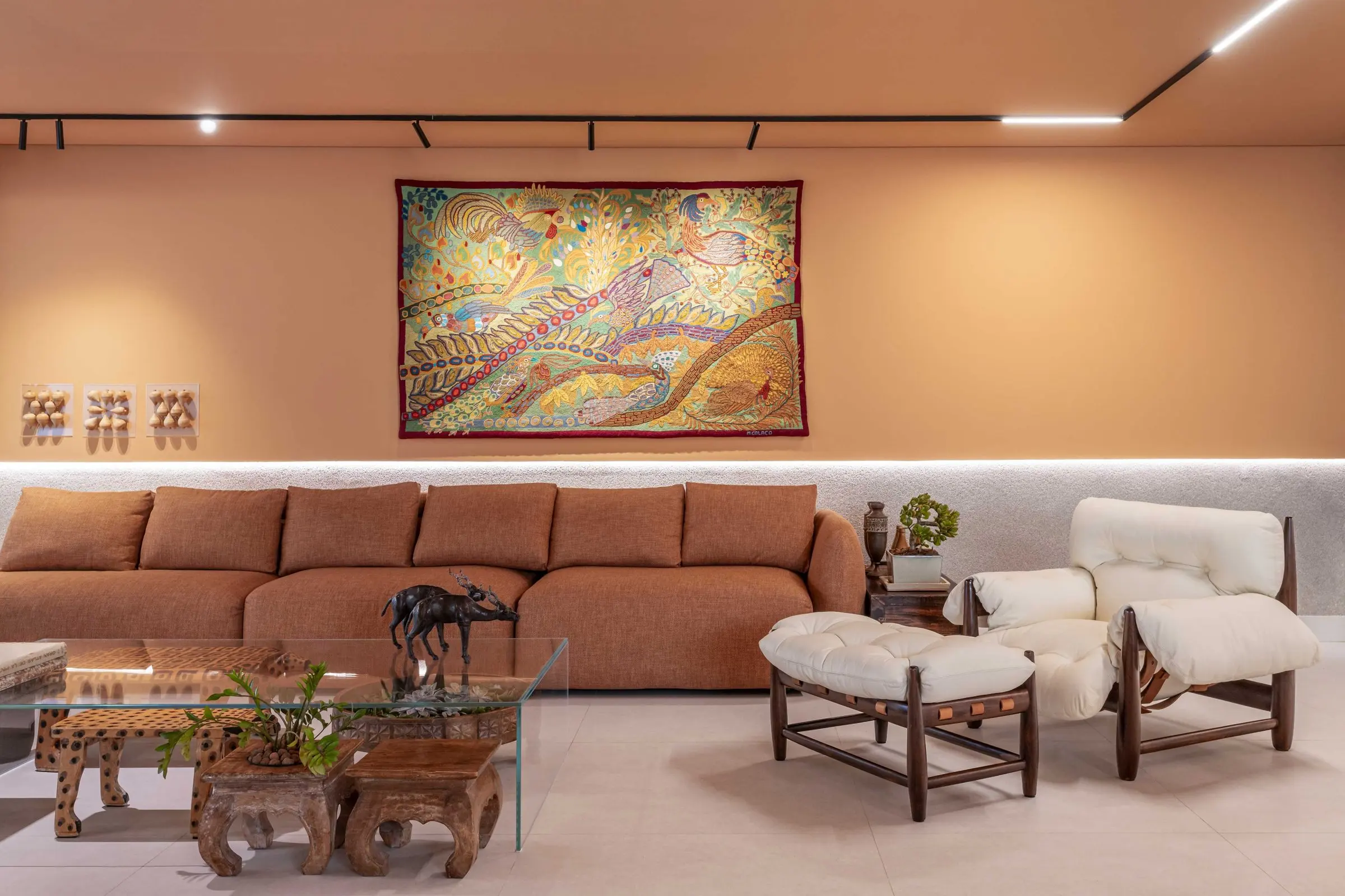 Sala de estar com sofá terracota, poltronas de madeira e grande tela colorida