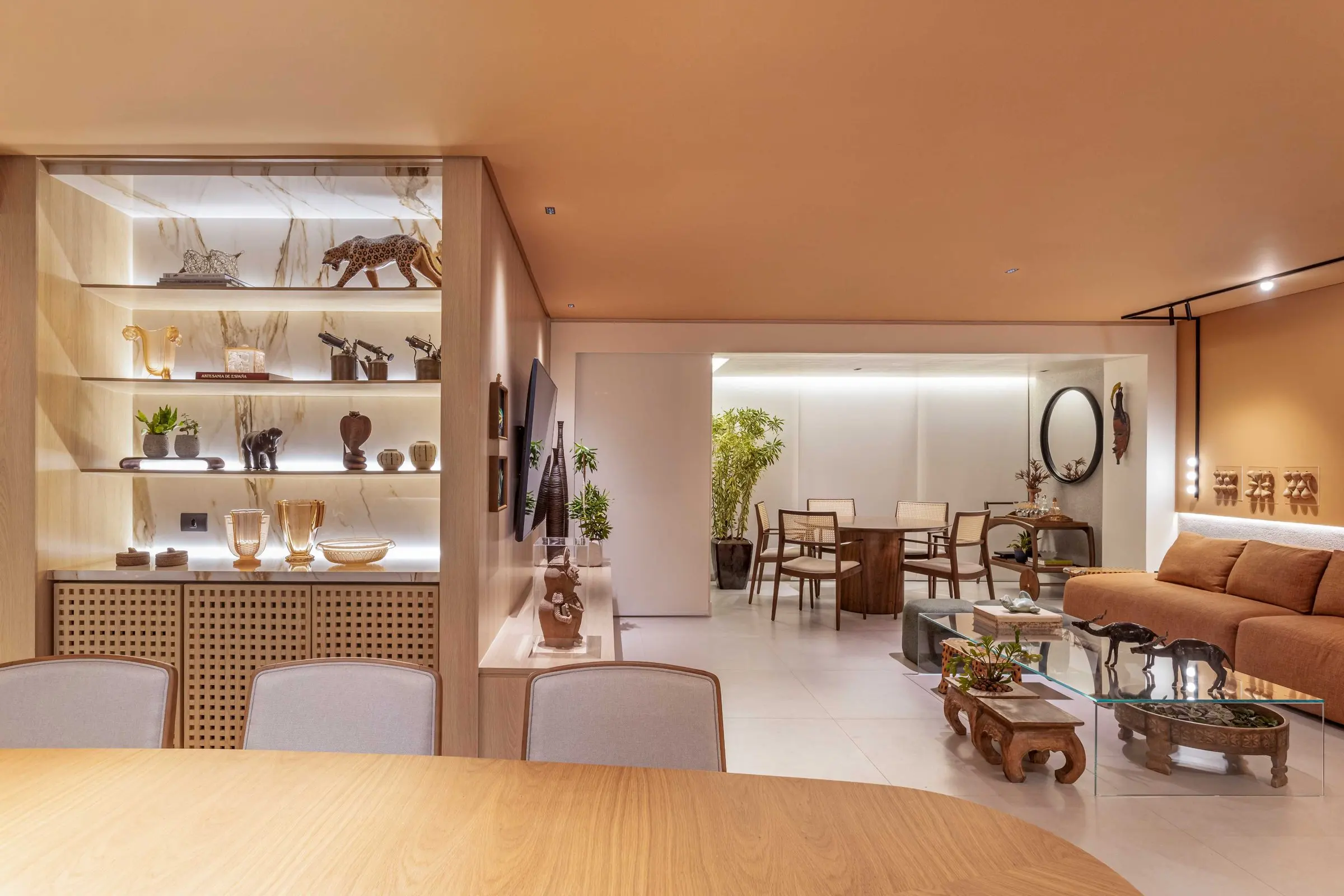 Estante vazada em madeira com esculturas e vista para a sala