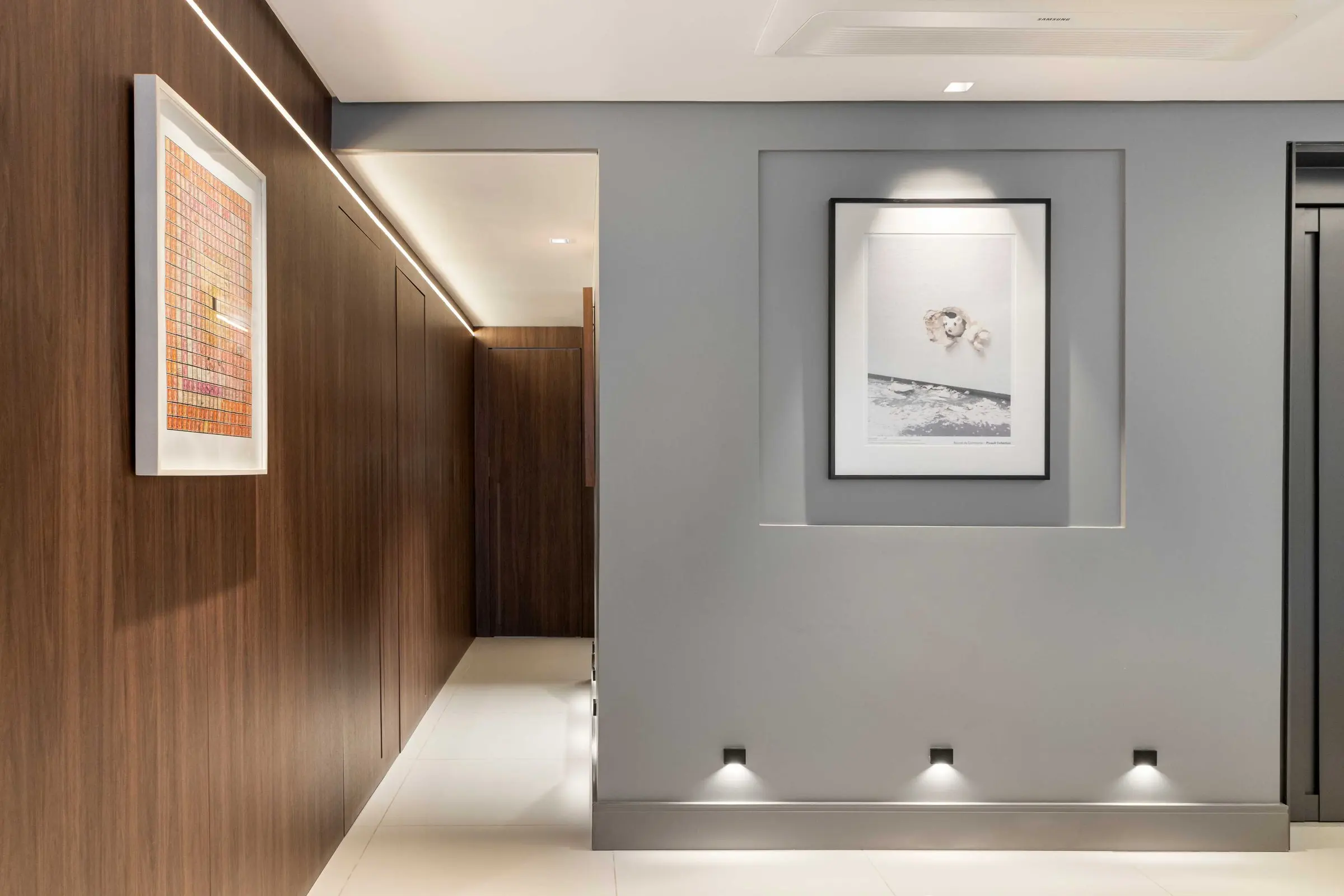 Hall com parede cinza, nicho iluminado e painel de madeira