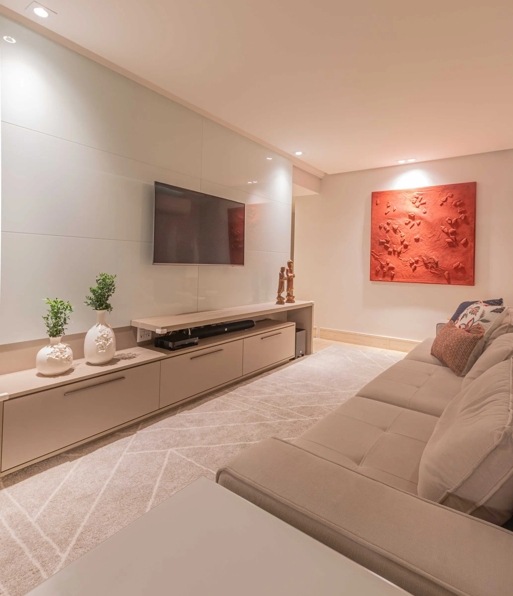 Sala de TV com sofá cinza e obra em relevo vermelha